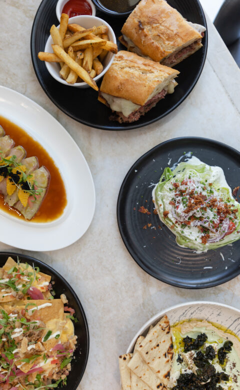 spread of dishes including nachos, french dip, hummas